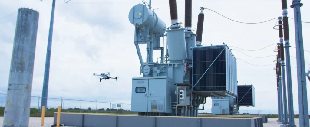 A drone flying an autonomous inspection past a substation transformer